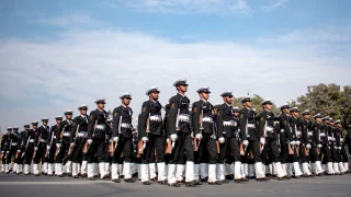 A disciplined contingent of Indian Navy sailors in black and white uniforms marching in synchronized formation with rifles during a parade in New Delhi.