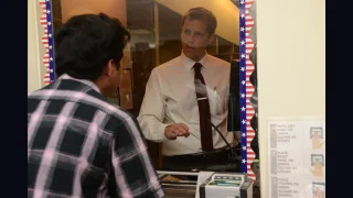  A US visa officer talking to an applicant at an official processing window equipped with a biometric fingerprint scanner and instructional signs.